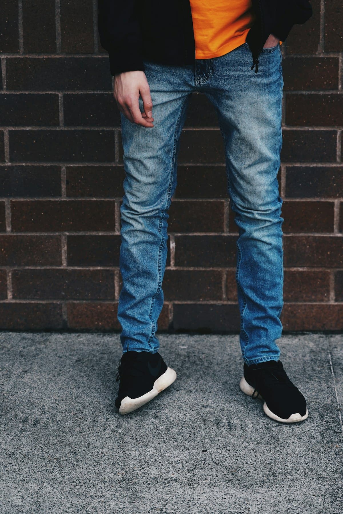 Homem vestindo calça jeans indigo e tênis preto