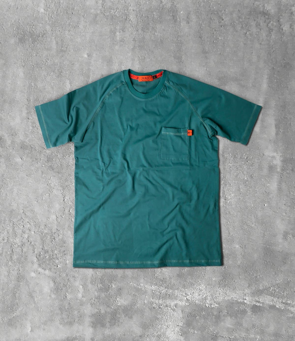 Camiseta verde petróleo estendida sobre fundo de concreto